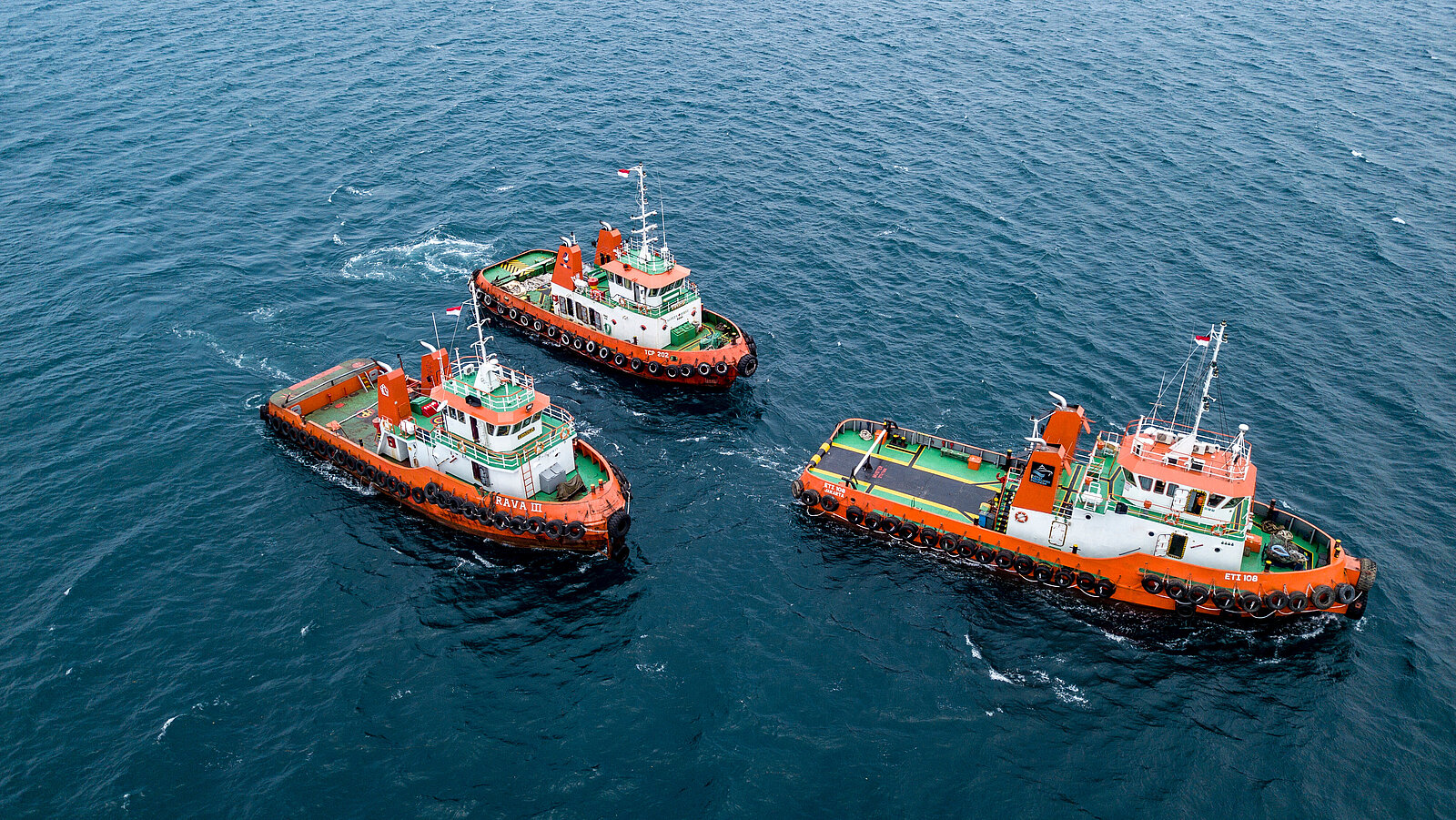 Three orange and white boats on calm water, one slightly ahead